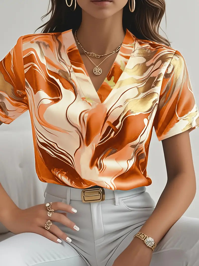 Orange marble print short sleeve shirt with v-neck, worn with white pants and gold accessories in an indoor setting.
