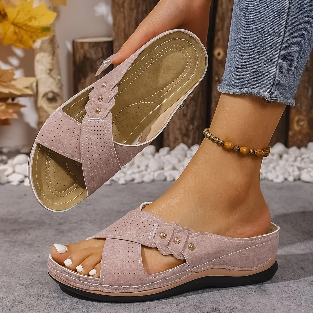 Pink orthopedic wedge sandals worn, with logs and autumn leaves in a cozy indoor setting.