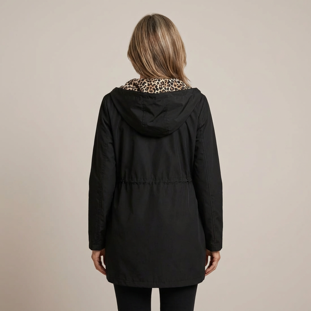 Back view of woman in black coat with leopard print collar, studio setting.