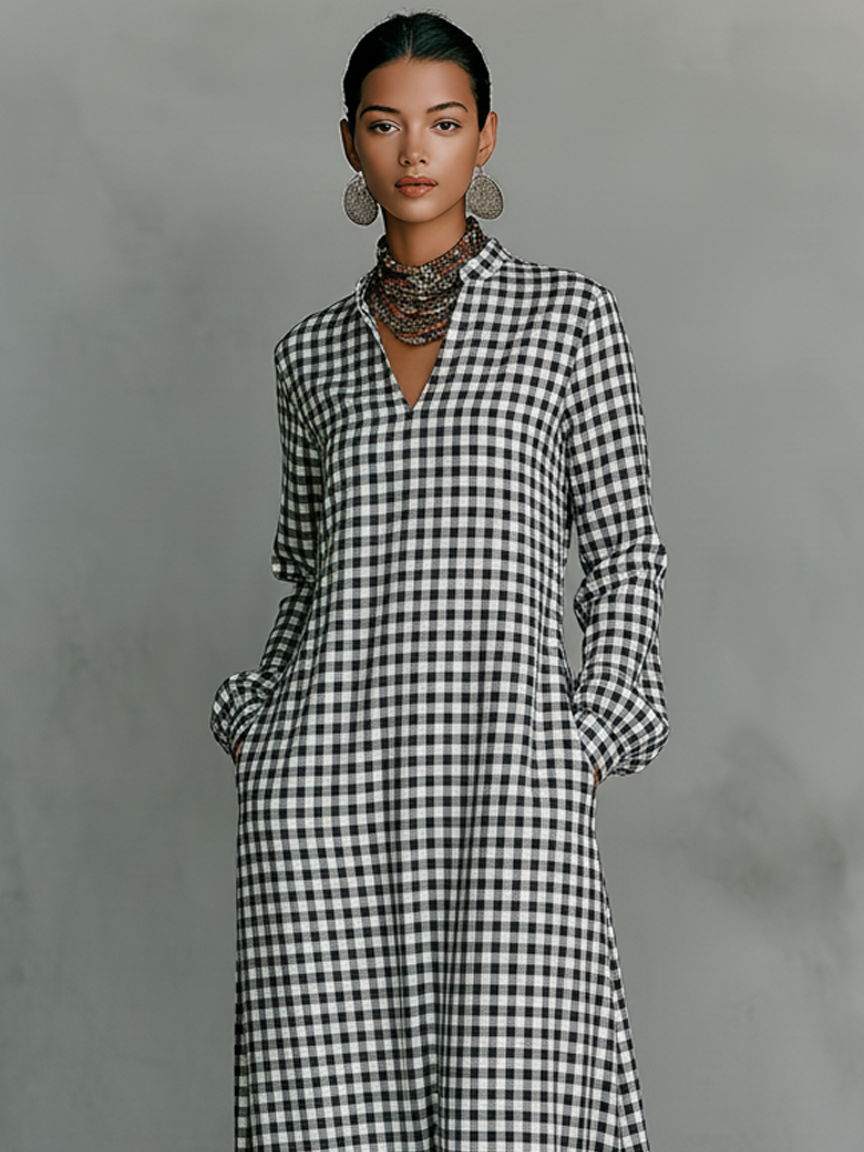 Model wearing black and white plaid V-neck maxi dress with long sleeves, accessorized with earrings and a necklace, in a studio setting.