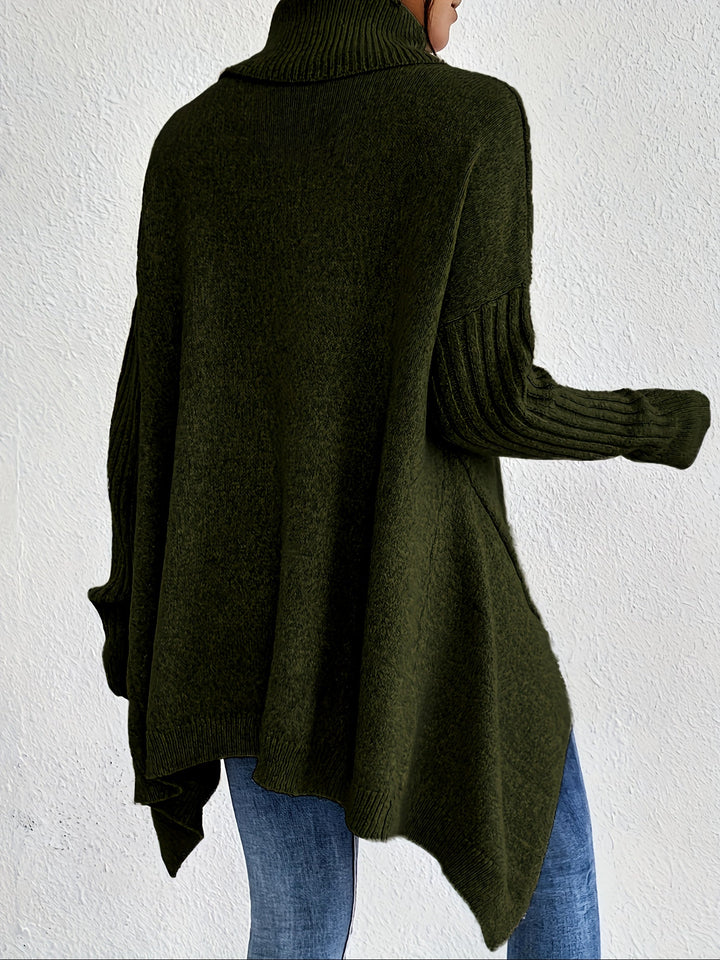 Back view of green turtleneck sweater with ribbed sleeves, worn with jeans, against a white wall.