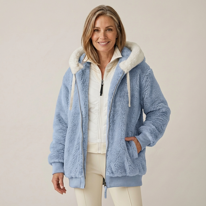 Woman wearing a plush, light blue hooded jacket with a white interior, in a studio setting.