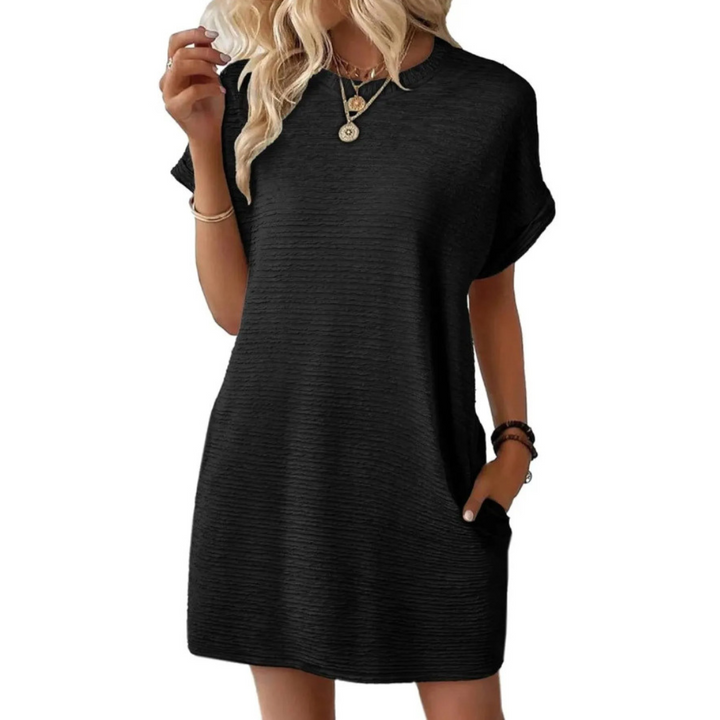 Sleek black casual dress with short sleeves and a relaxed silhouette, accessorized with necklaces in a studio setting.