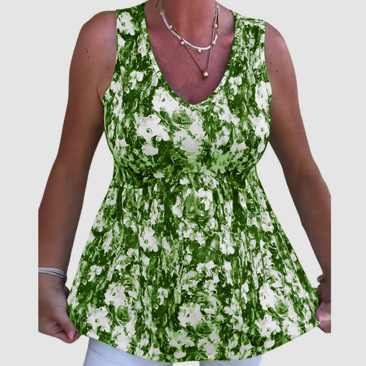 Woman wearing a green and white abstract pattern sleeveless top, adjusting the hem in a studio setting.