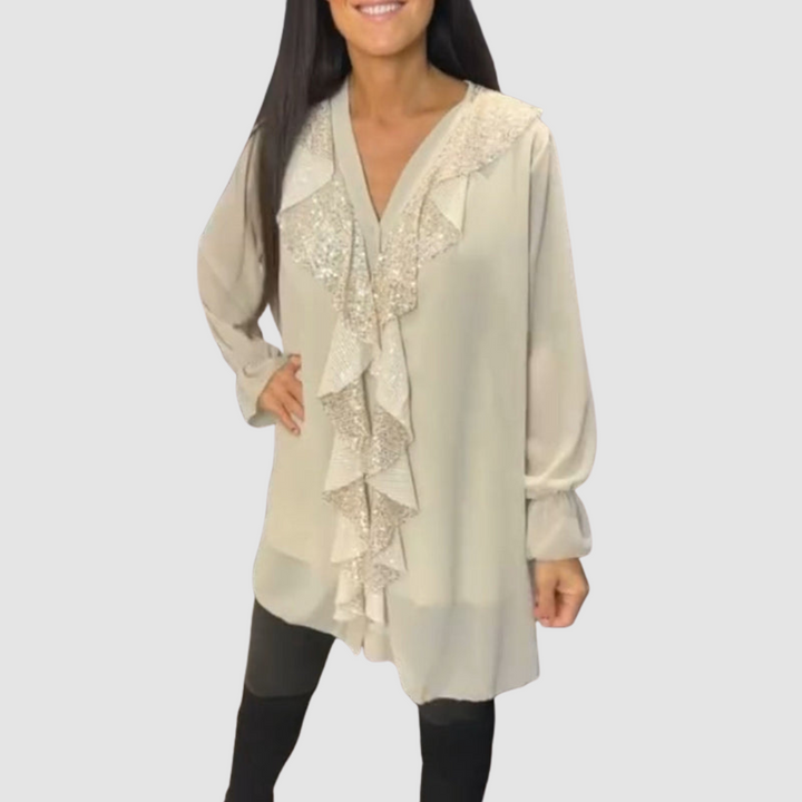 Cream blouse featuring ruffles and shimmering details, worn with leggings in a studio.