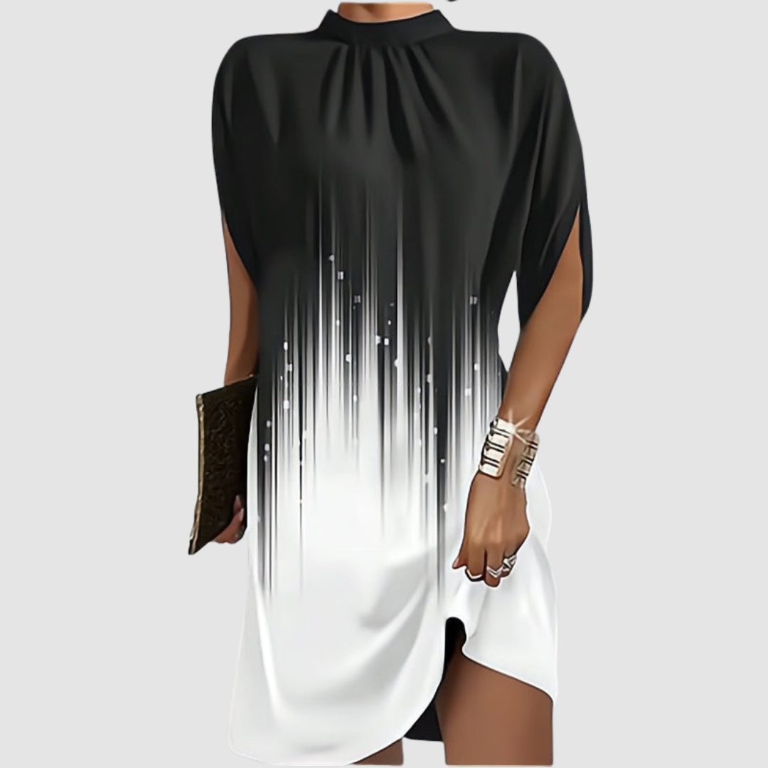 Black and white gradient knee-length dress with a loose fit and high neckline, styled with gold bangles and clutch on gray.