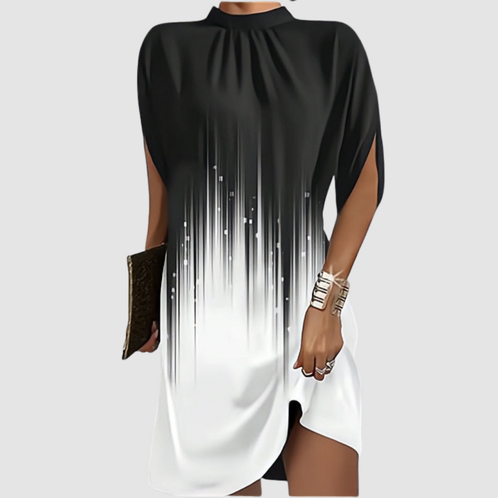 Black and white gradient knee-length dress with a loose fit and high neckline, styled with gold bangles and clutch on gray.
