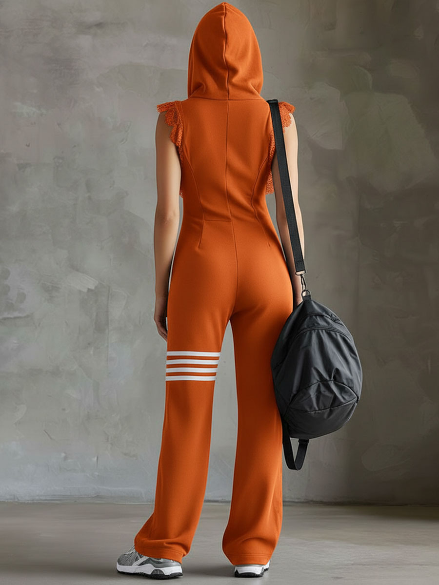 Back view of model in orange hooded jumpsuit, holding bag, studio backdrop.