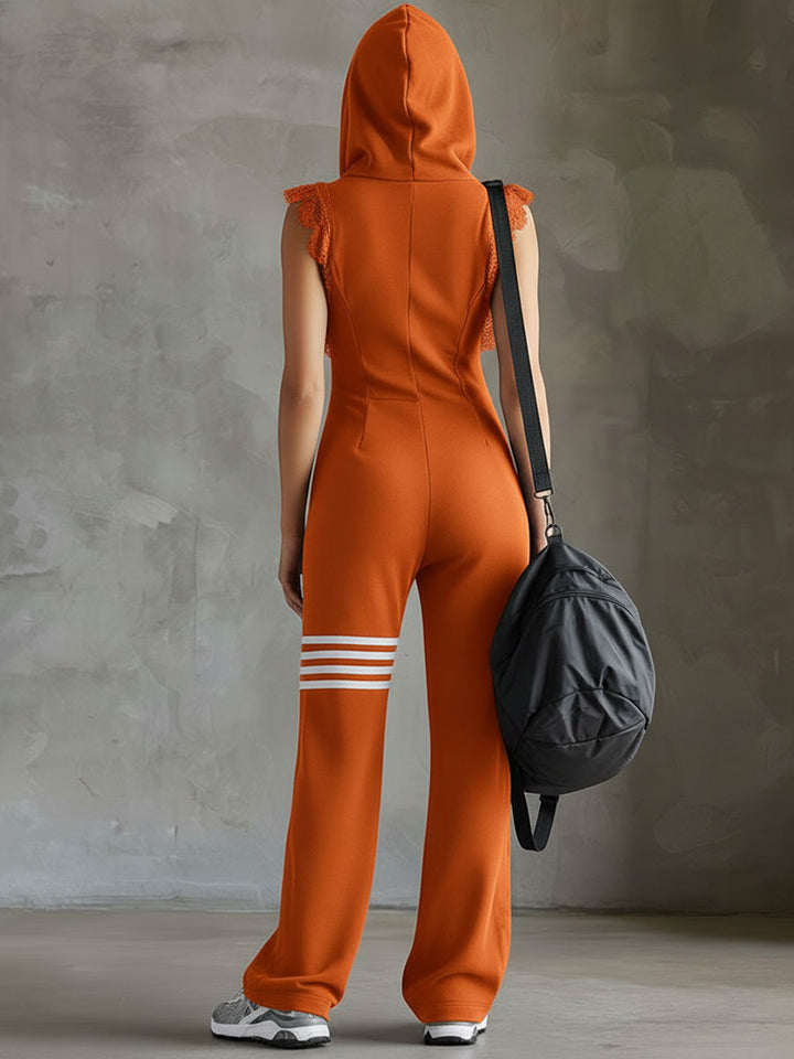 Back view of model in orange hooded jumpsuit, holding bag, studio backdrop.