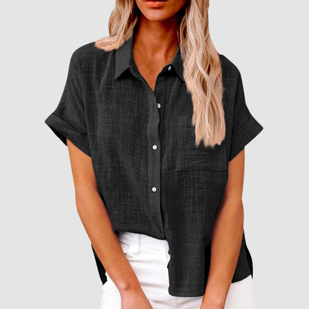 Black casual blouse with short sleeves and front buttons, worn in white jeans. Studio background.