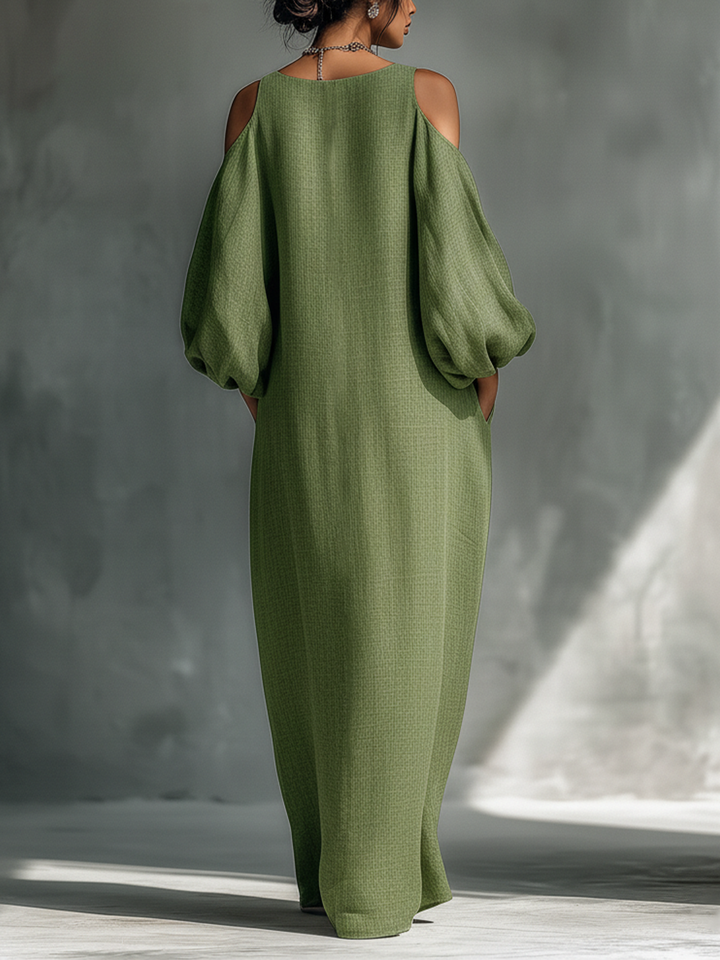 Back view of a green maxi dress with cutout shoulders and puff sleeves, modeled in a studio.
