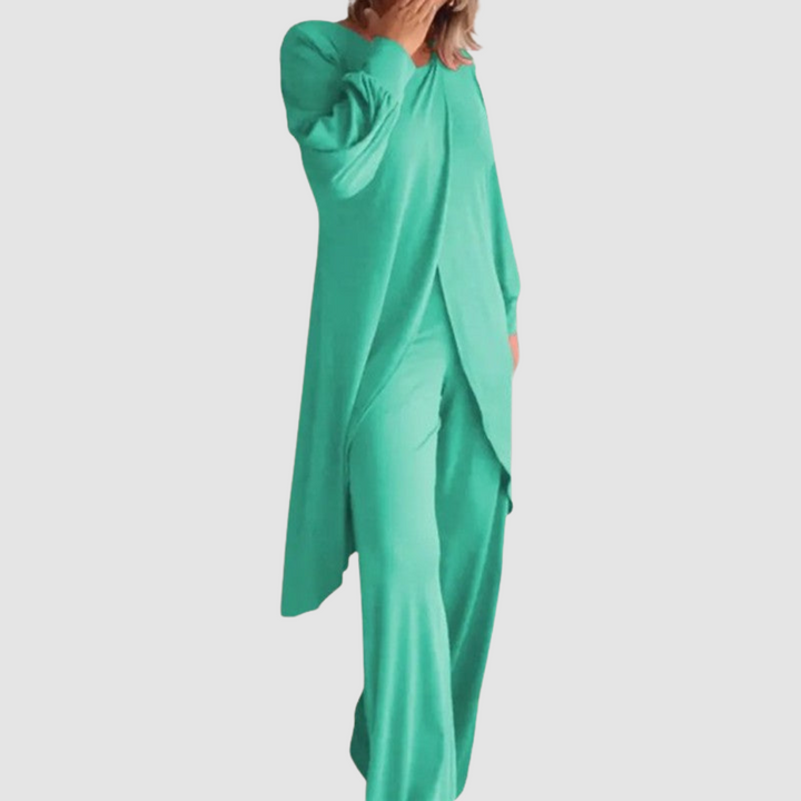 Model wearing a green long-sleeve 2-piece set in a studio, hand covering face, white background.