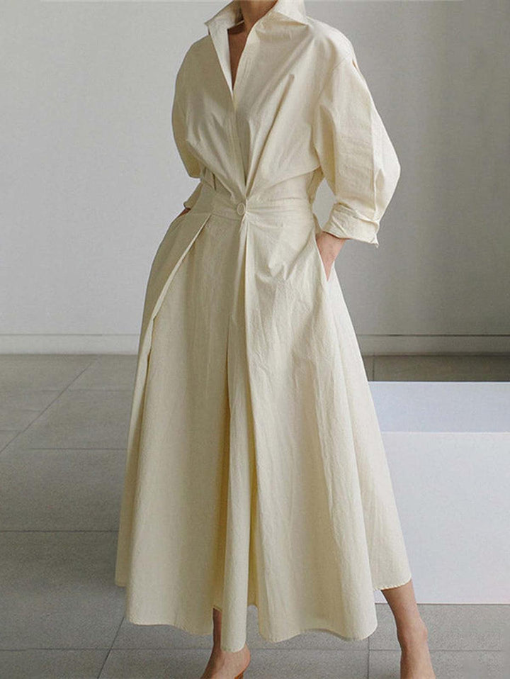 Elegant midi dress in cream with button lapel and loose fit, worn indoors on tile floor.