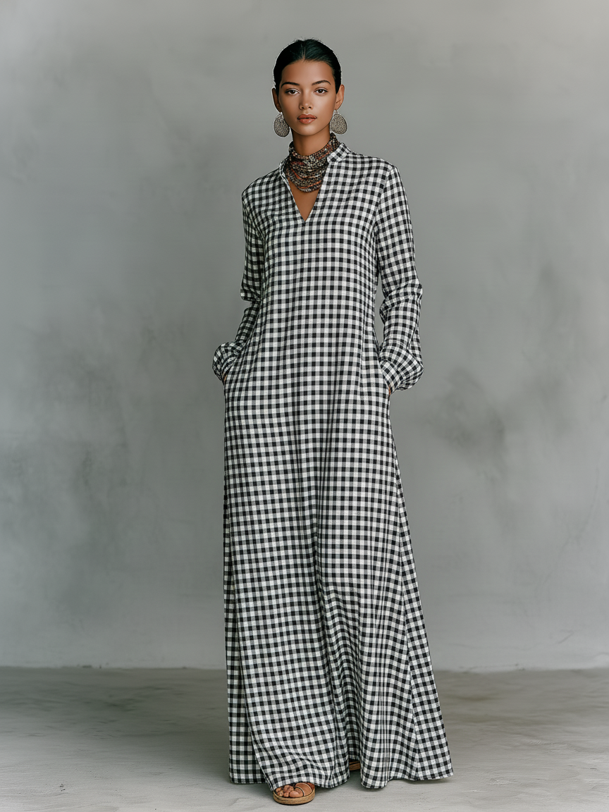 Full view of black and white plaid V-neck maxi dress on model in a studio with gray textured background.