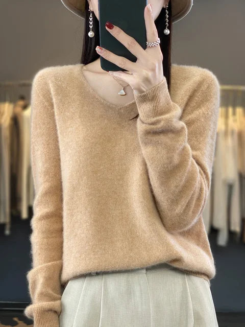 Person wearing a beige loose knit sweater, set against a fashion studio backdrop.