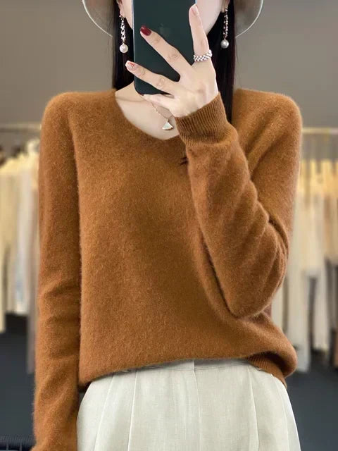 Person wearing a rust-colored loose knit sweater, standing in a fashion studio.
