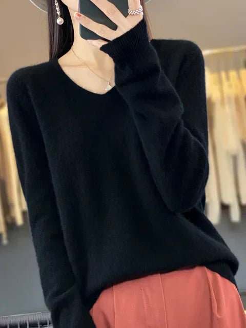 Person in a sleek black loose knit sweater, standing in a stylish studio.