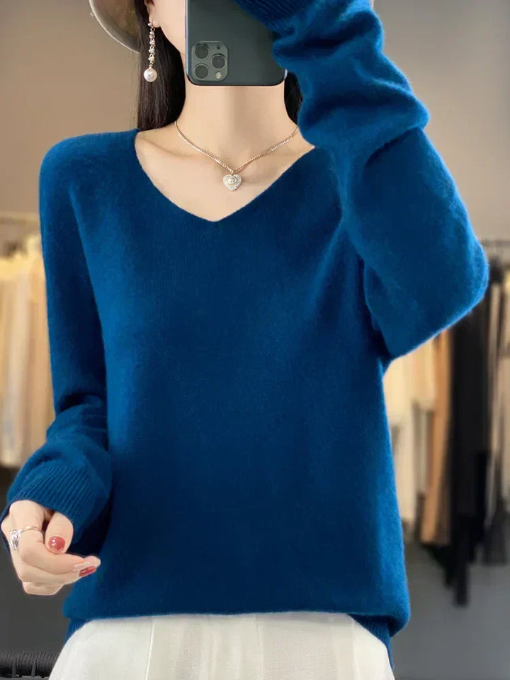 Person in a deep blue loose knit sweater, posed in a modern fashion studio.