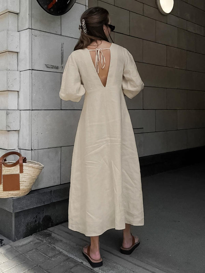 Woman in cream buttoned maxi dress standing in urban setting, showing dress&
