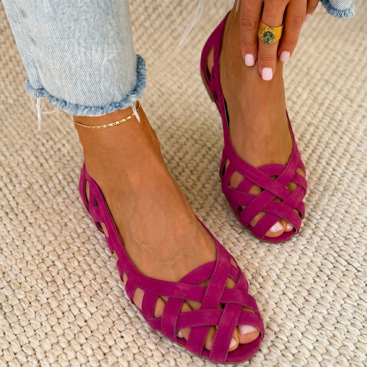 Pink comfort sandals with woven design worn on a carpeted floor, paired with light denim jeans.