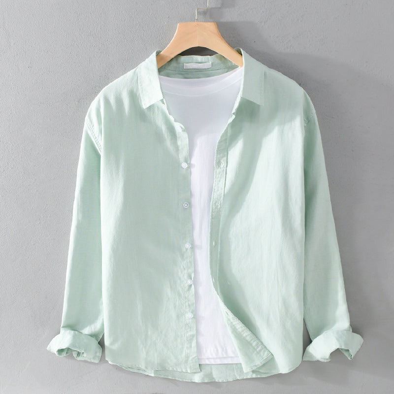 Light green shirt over white tee on hanger against gray wall.