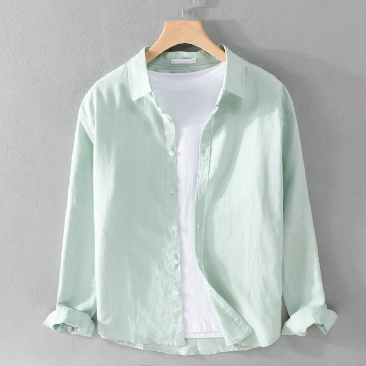 Light green shirt over white tee on hanger against gray wall.