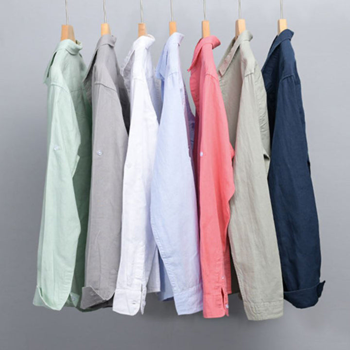 Row of shirts in different colors hanging on wooden hangers.