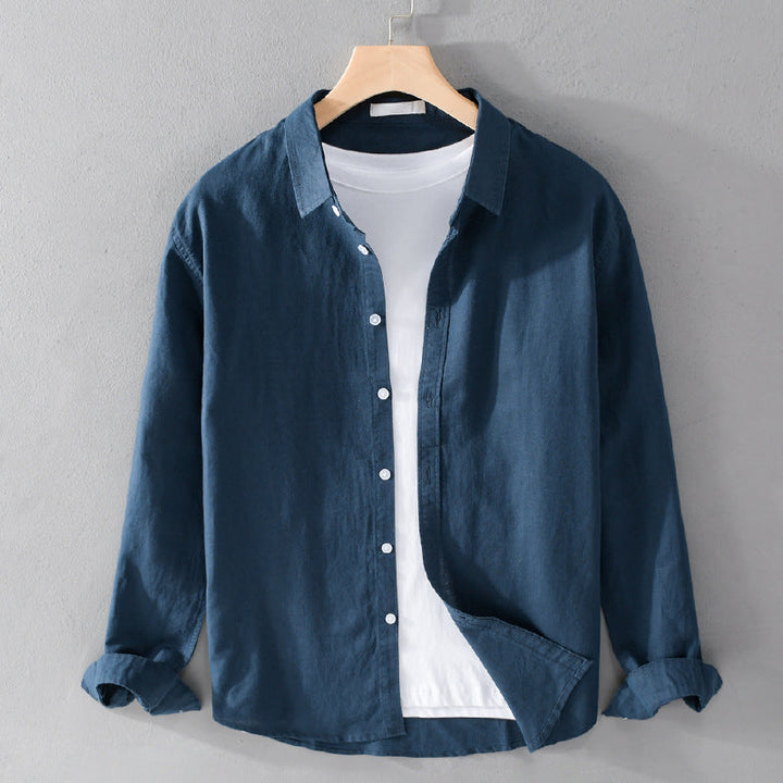 Dark blue shirt over white tee on hanger against gray wall.
