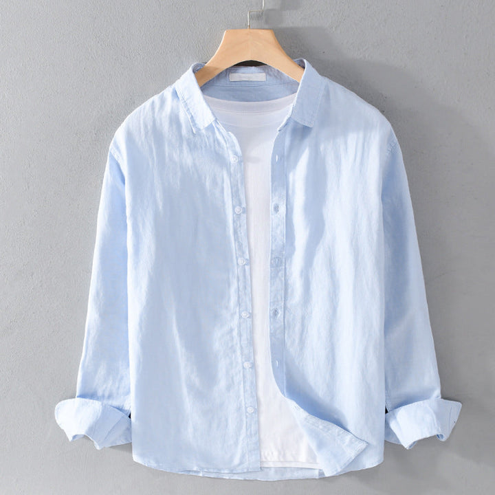 Light blue shirt over white tee on hanger against gray wall.