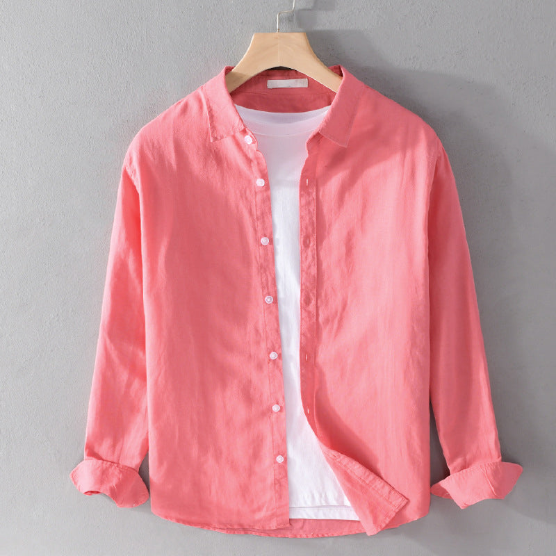 Pink shirt over white tee on hanger against gray wall.