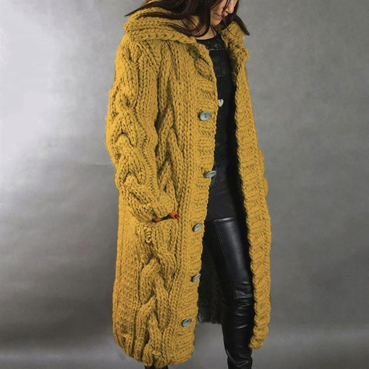 Mustard yellow knitted coat with buttons, worn by a person in leather pants, studio setting.