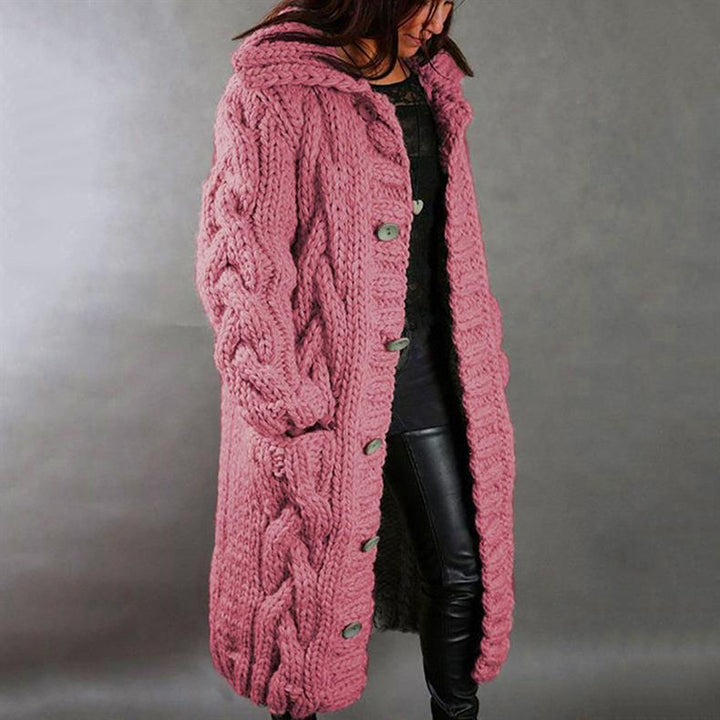 Pink knitted coat with buttons, worn by a person in leather pants, studio setting.