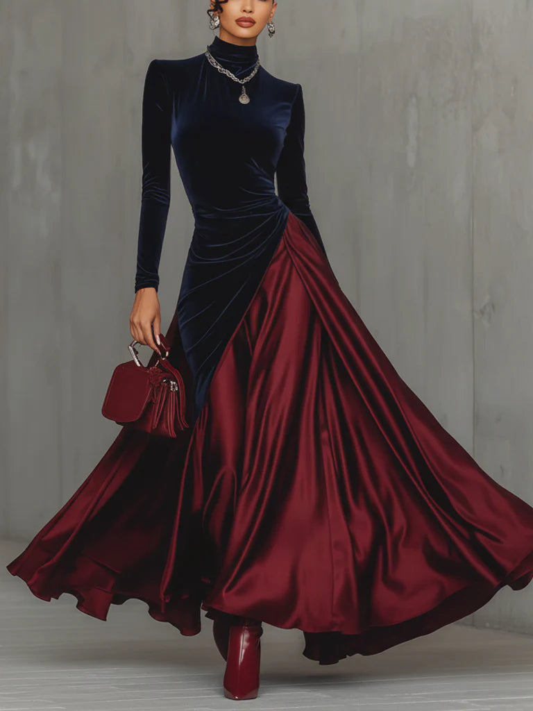 Elegant dress with a navy fitted top and flowing maroon skirt, accessorized with jewelry and a handbag, against a gray background.