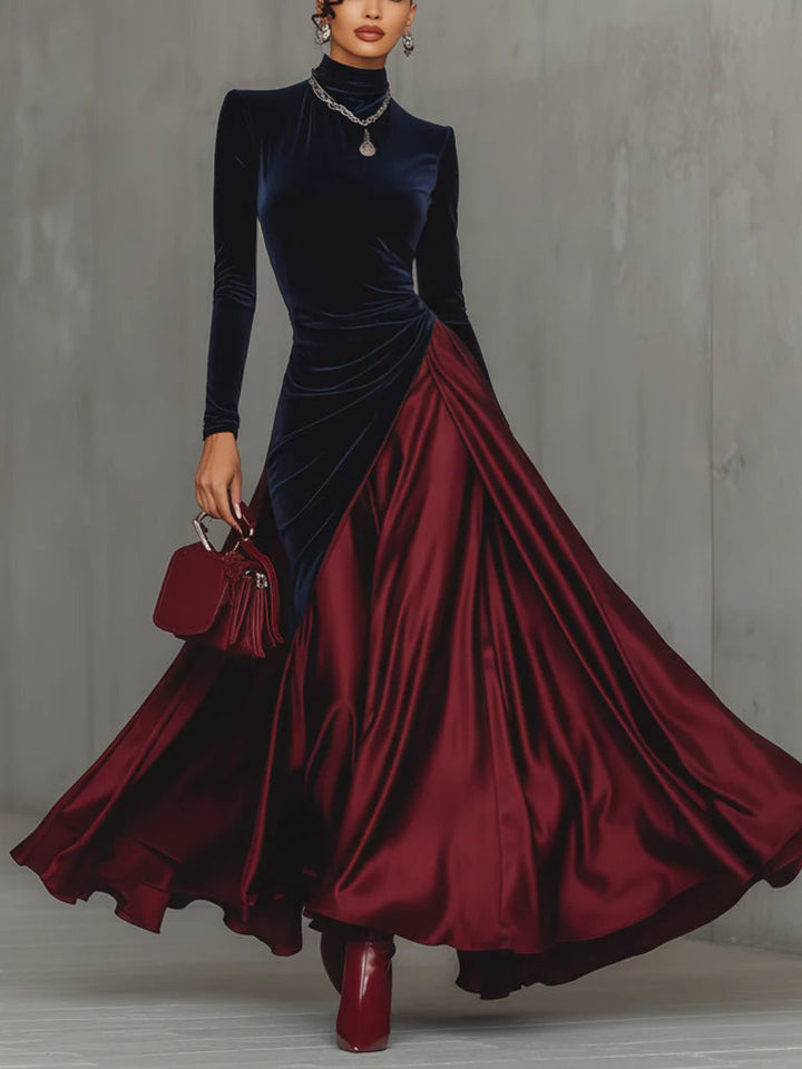 Elegant dress with a navy fitted top and flowing maroon skirt, accessorized with jewelry and a handbag, against a gray background.