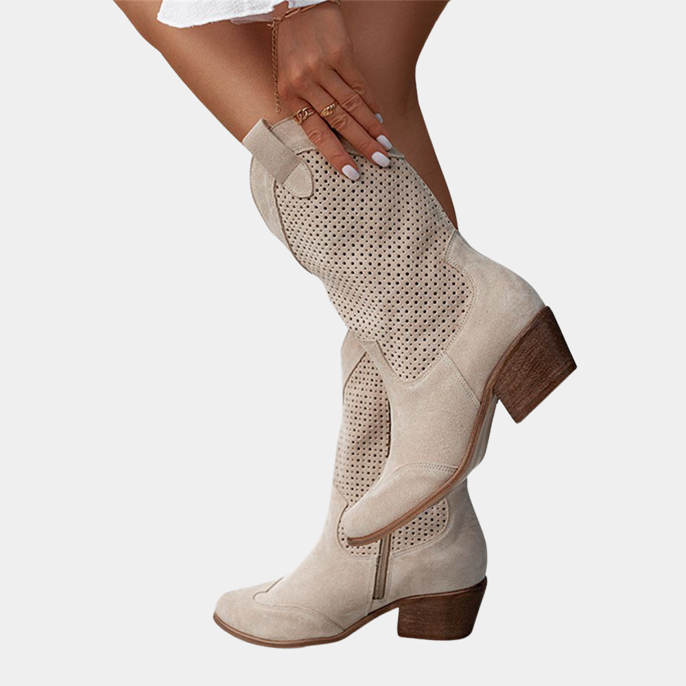 Close-up of beige perforated cowboy boot with wooden heel against a white background.