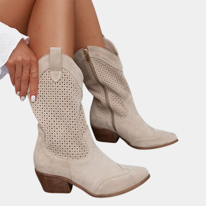 Pair of beige perforated cowboy boots with wooden heels on white background.