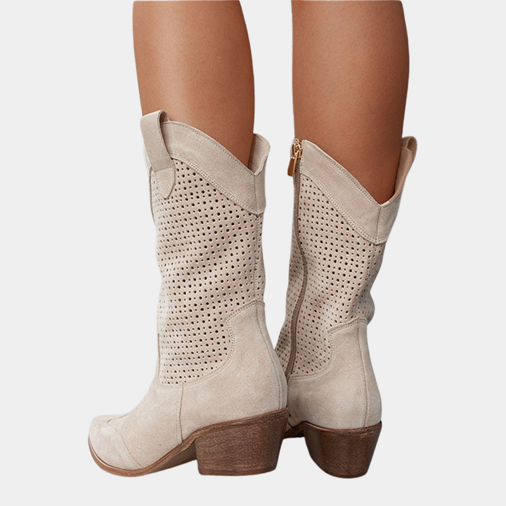 Back view of beige perforated cowboy boots with wooden heels on white background.