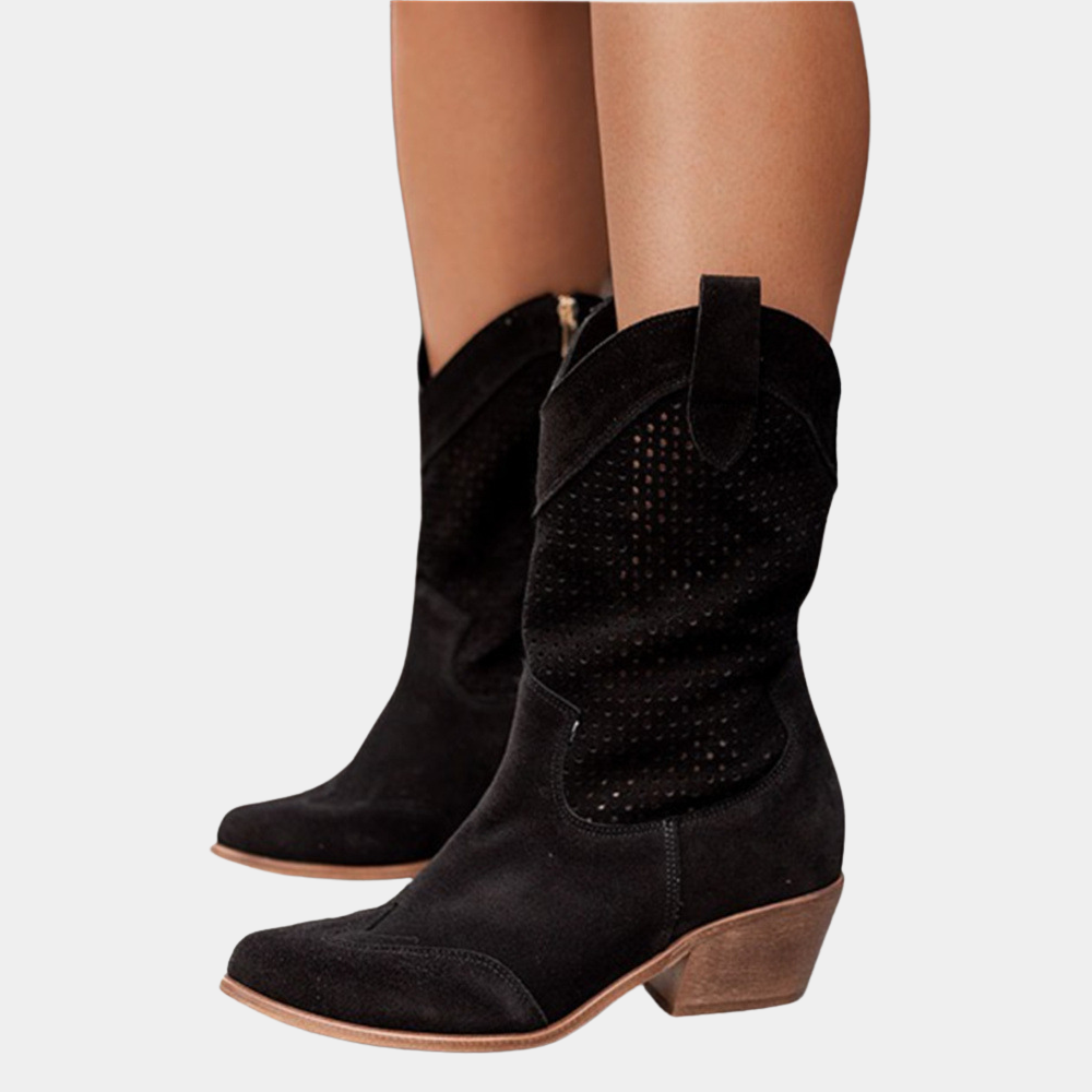 Black perforated cowboy boots with wooden heels on white background.