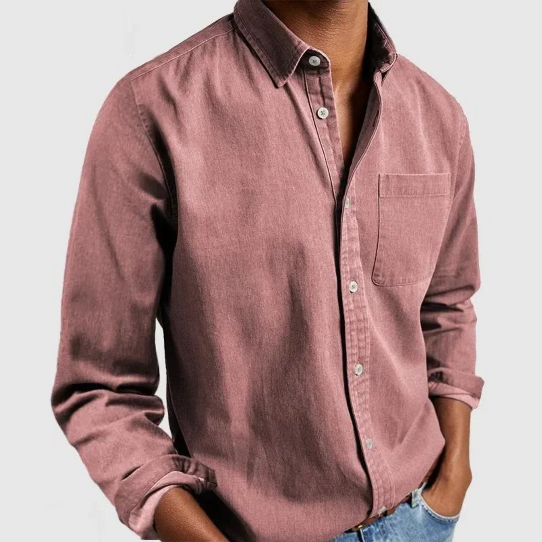 Pink button-up shirt with front pocket and rolled sleeves, styled with hands in pockets; gray background.