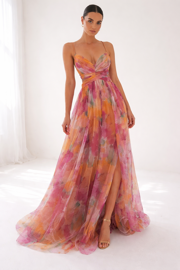 Flowing dress with pink, orange hues, thin straps, studio setting, bright natural light.