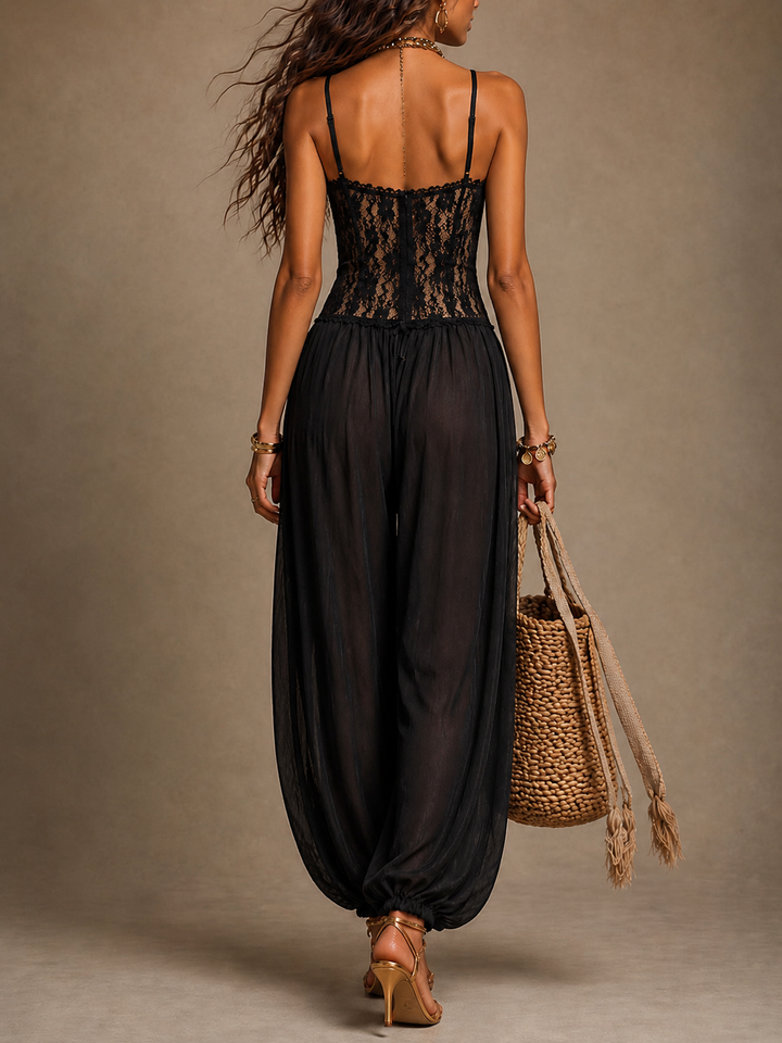 Back view of woman in black lace halter jumpsuit with flowing pants and a straw bag, photographed in studio.