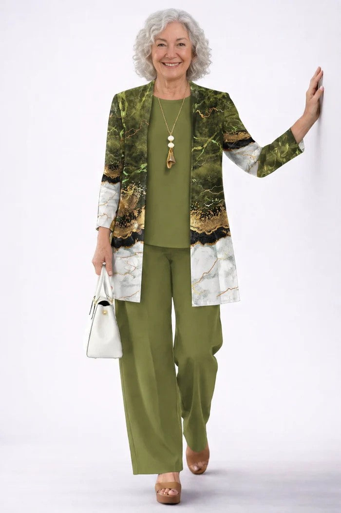 Woman in a green three-piece set with a marble effect cardigan. White studio background.