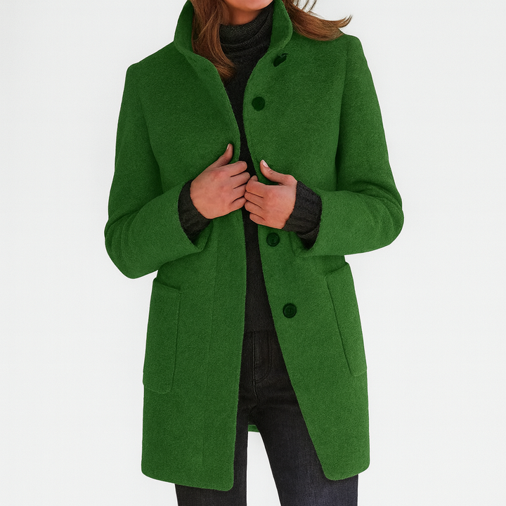 Rich green elegant coat with high collar and button closure, worn by model with dark turtleneck and pants in studio setting.