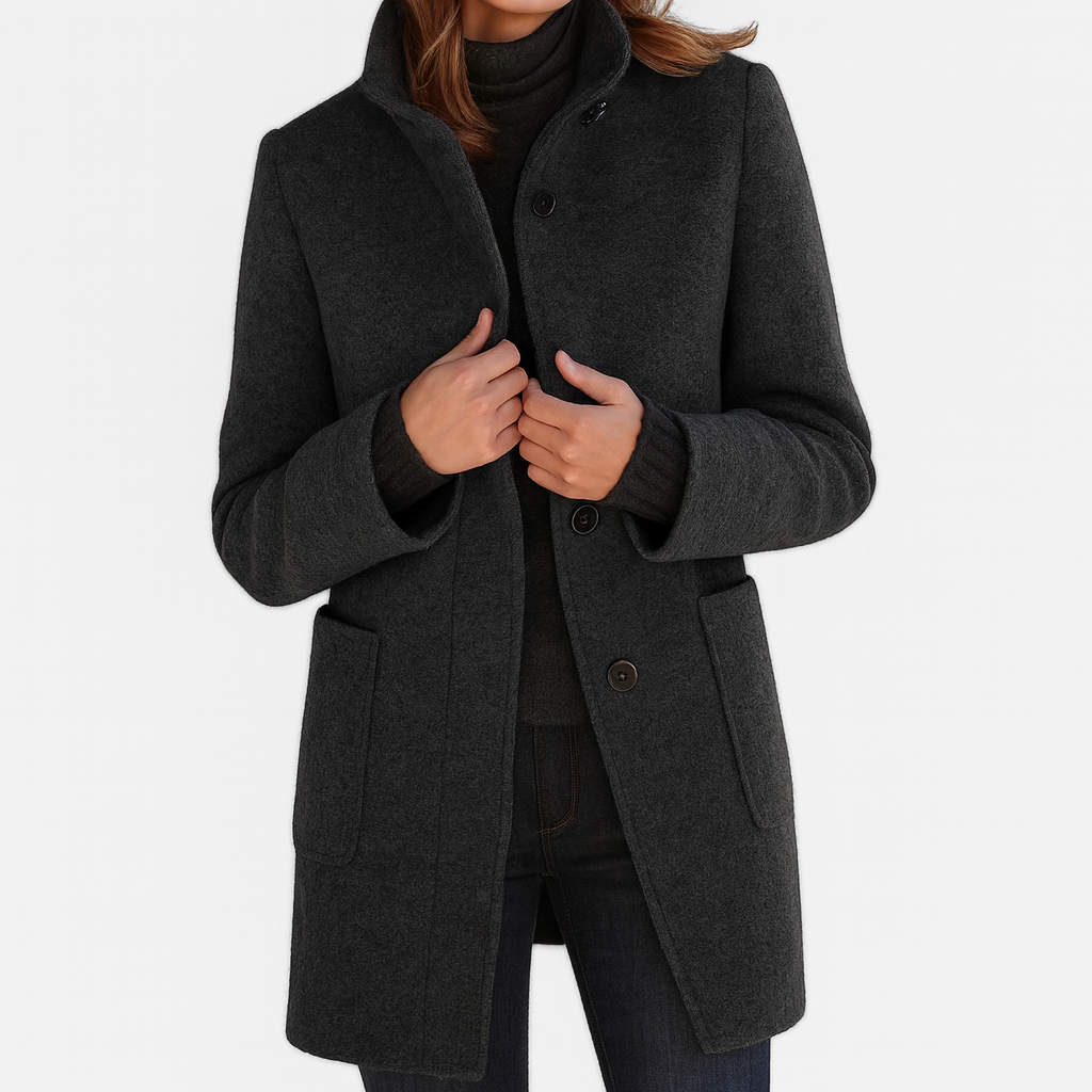 Classic black elegant coat with high collar and button closure, worn by model with dark turtleneck and pants in studio setting.