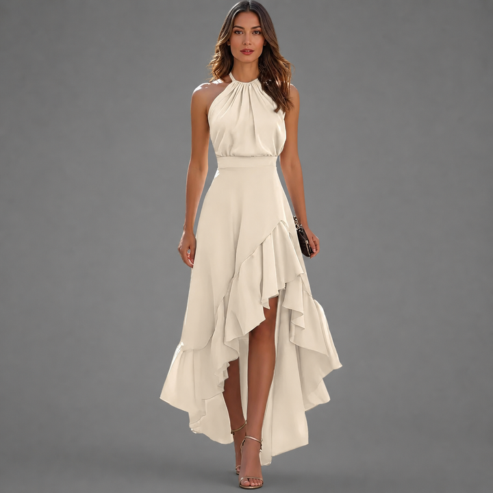 Elegant off-white maxi dress with halter neck and asymmetrical ruffled hem, modeled against a gray studio backdrop.