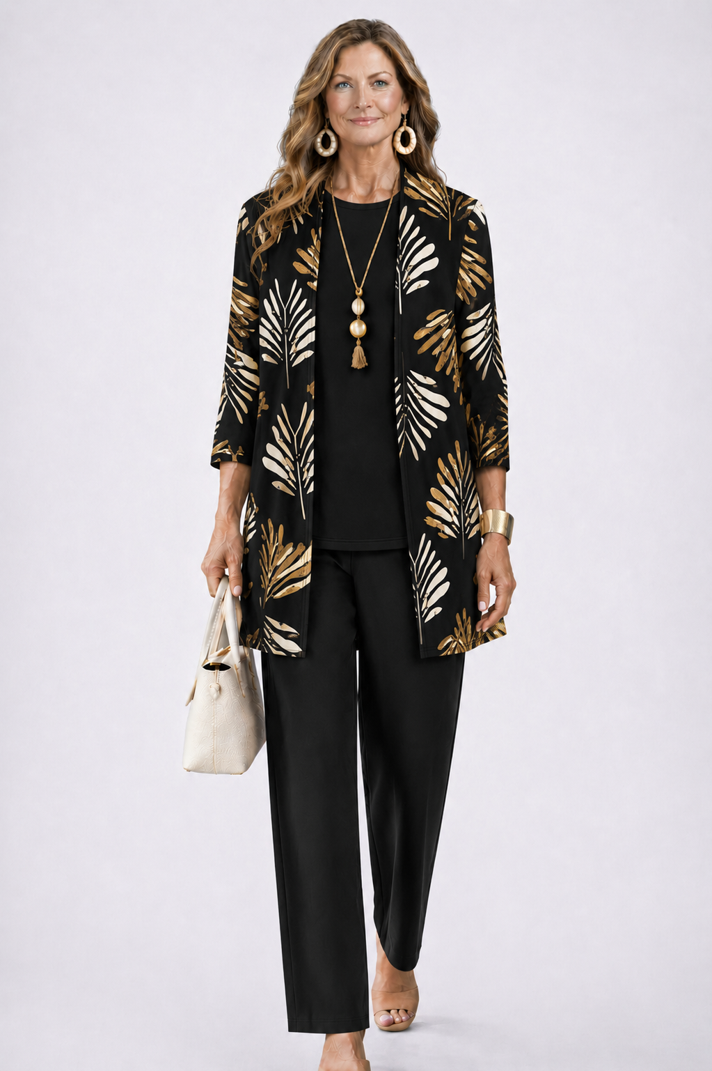 Woman in a black three-piece set with a gold leaf pattern cardigan. White studio background.