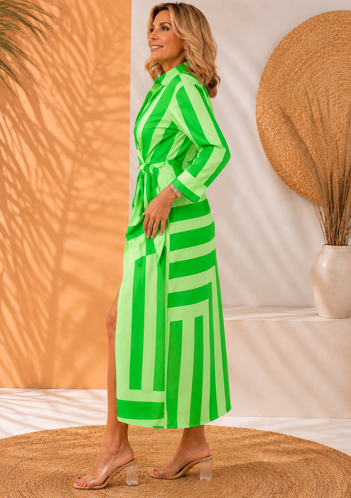 Side view of model in green striped maxi dress, standing on woven rug.