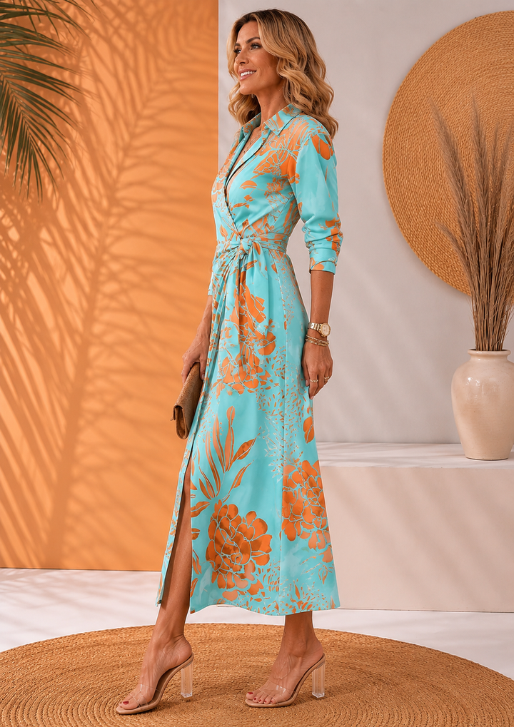 Side view of model in blue dress with orange floral print, holding clutch on woven rug.