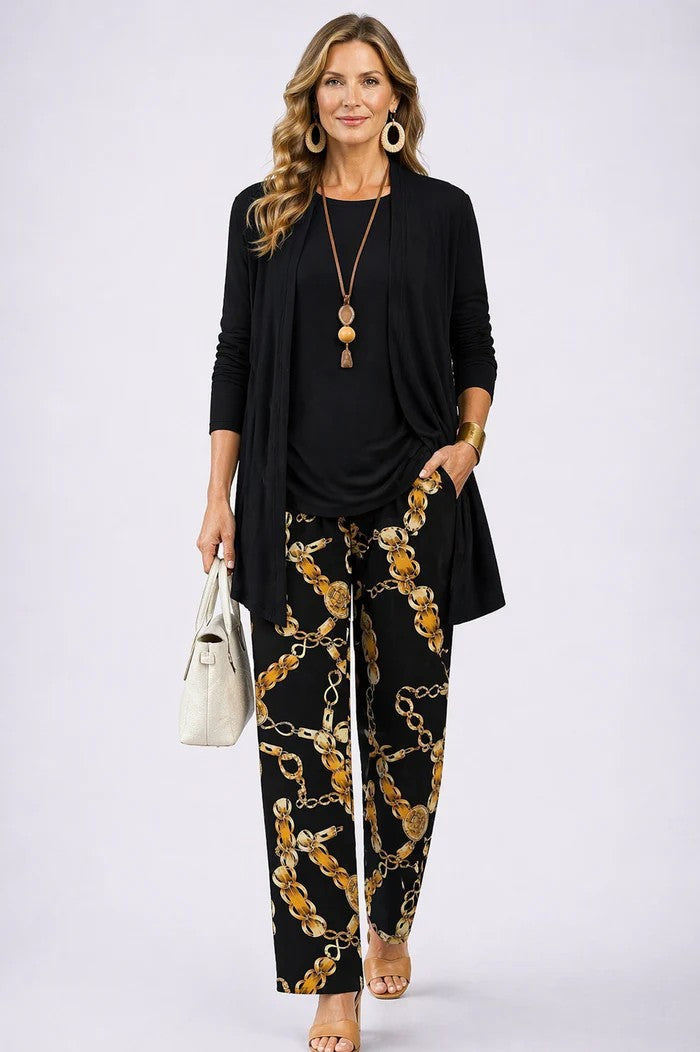 Woman in a black three-piece set with chain pattern pants. White studio background.
