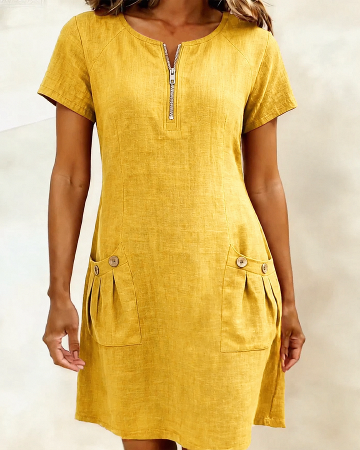 Yellow short-sleeve dress with zipper and buttoned pockets in a studio backdrop.